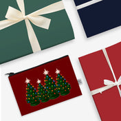 Red pouch with Christmas tree design, green gift box with white ribbon, and red gift box with white ribbon on a white background.