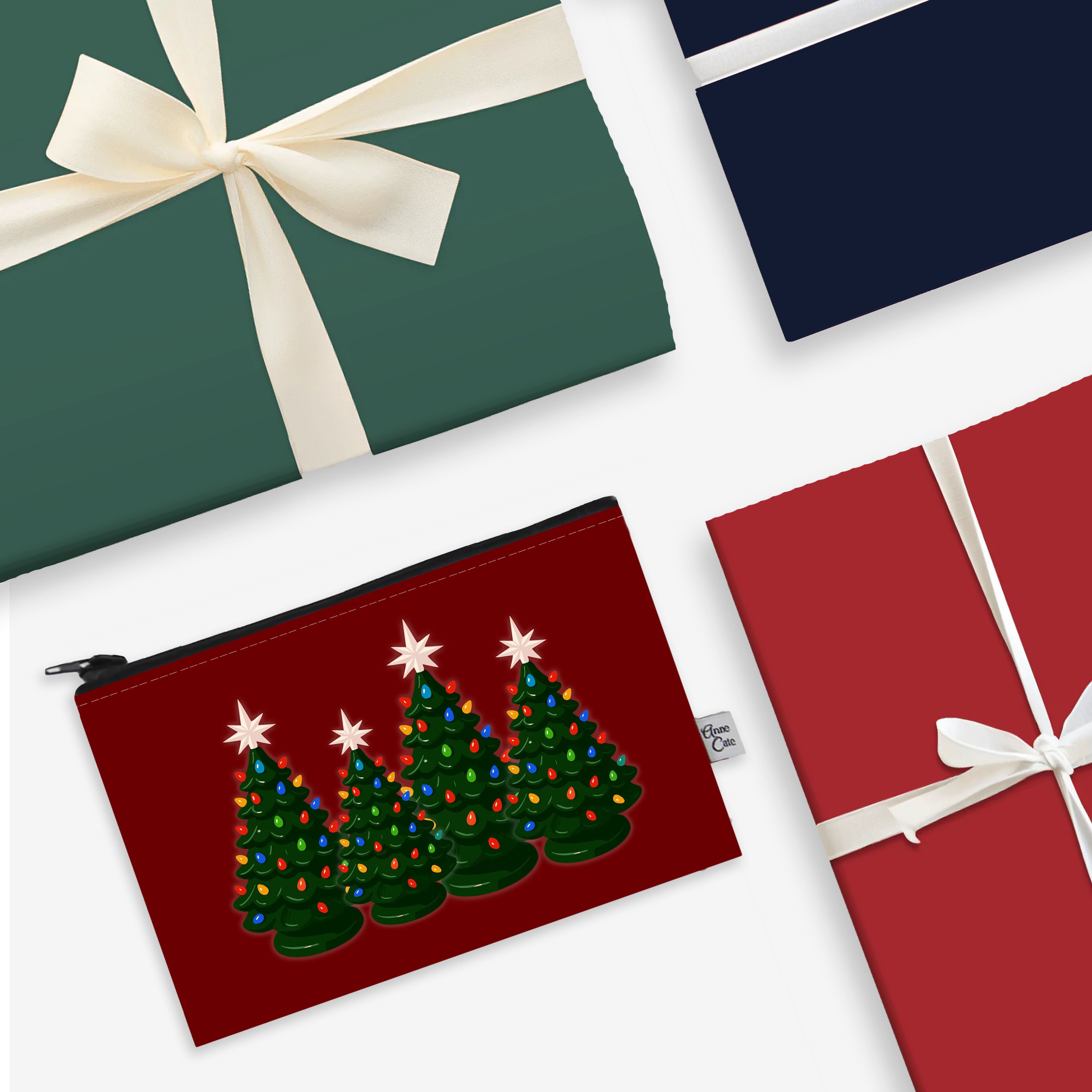 Red pouch with Christmas tree design, green gift box with white ribbon, and red gift box with white ribbon on a white background.